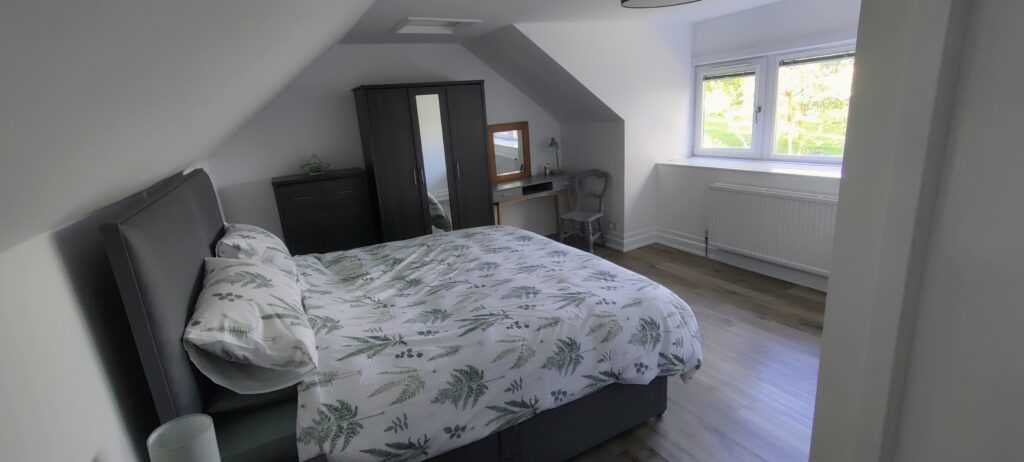 Bedroom - super kingsize configuration showing chest of draws, wardrobe, dressing table and window.